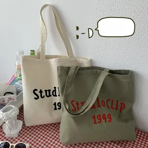 Detailed view of canvas tote bags with Studio Clip 1949 text and olive green texture