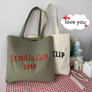 Close-up of olive green canvas tote bag featuring premium red Studio CLIP 1949 embroidery