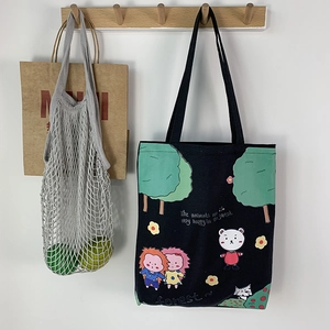 Detail view of a black canvas tote bag with cartoon forest illustrations and tree patterns