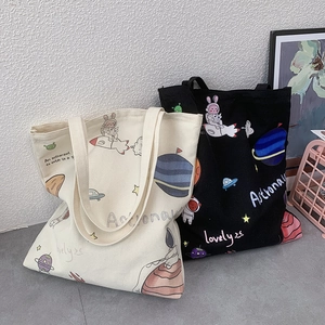 Detail of canvas tote bags featuring cute astronaut and space planet prints in black and white