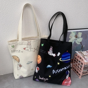 Detail view of canvas tote bags with astronaut prints in cream white and black colors