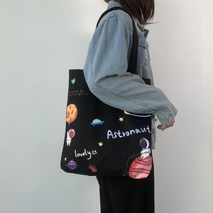 Detail of black canvas tote bag featuring astronaut and space cartoon illustration