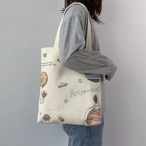 Detail of canvas tote bag with astronaut illustration and woven fabric texture