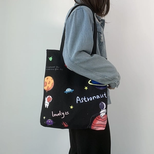 Detail of a black canvas tote bag with colorful astronaut and space theme patterns