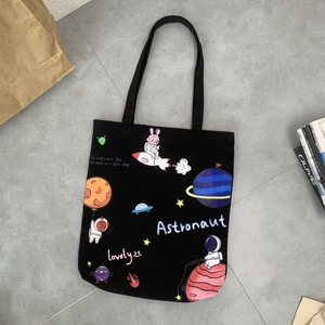 Detail of black canvas tote bag with cartoon astronaut rabbit print and space theme graphics