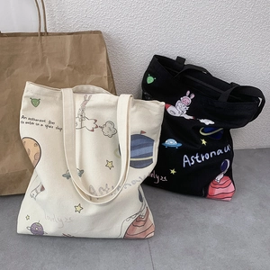 Detail of canvas tote bags in black and beige with cartoon astronaut space prints