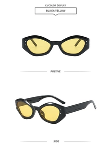Detail of geometric cat-eye sunglasses with black frame, yellow lenses and metal accents
