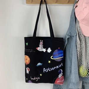 Detail of black canvas tote bag featuring colorful astronaut and space cartoon graphics