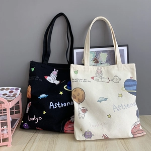 Detail of canvas tote bags with hand-drawn astronaut and space-themed cartoon patterns
