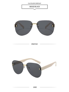 Detail view of beige rimless aviator sunglasses with black gradient lenses and gold accents