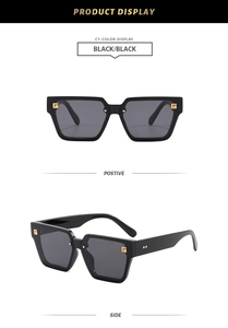 Detail view of square black sunglasses showing gold G-logo and polished finish
