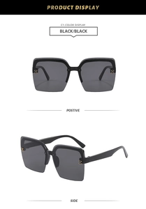 Close-up of black oversized square sunglasses featuring a signature golden H-shaped hinge