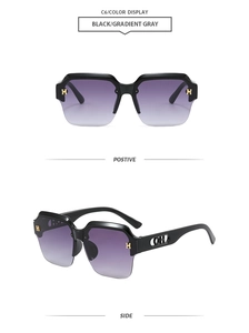 Detail of black semi-rimless sunglasses with gold H-accents and gradient gray lenses
