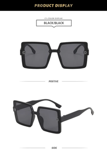 Detail of square black sunglasses showing the silver metal G-logo hinge and sleek design