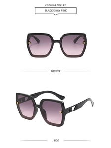 Detail view of square black sunglasses with gradient gray-pink lenses and gold metal accents