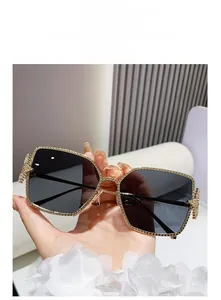 Detail of square sunglasses featuring golden chain texture frames and dark gray lenses