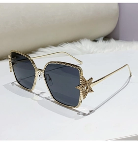 Close-up of gold square sunglasses featuring star decor and textured metal frame