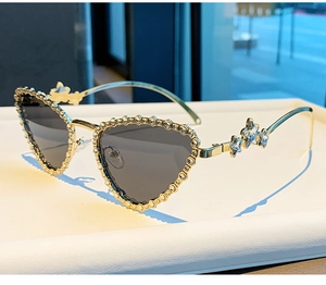 Détail de lunettes de soleil cœur œil de chat avec monture dorée et étoiles strass