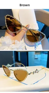 Détail de lunettes de soleil œil de chat marron avec monture dorée et papillon en strass