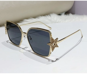Detail of gold metal frame sunglasses featuring a large hollow star decoration
