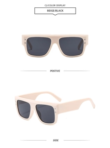 Detail view of beige square sunglasses with black lenses and decorative metal rivets