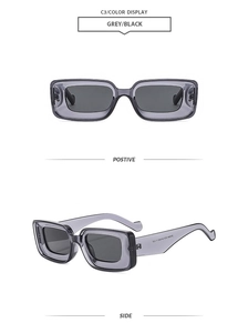 Detail view of grey transparent rectangular sunglasses with thick frames and black lenses
