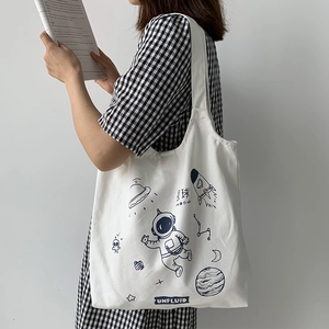 Detail view of white canvas tote bag featuring hand-drawn space theme astronaut illustrations