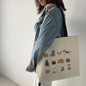 Détail du sac cabas en toile avec motifs de chats et bandoulière noire sur un mannequin
