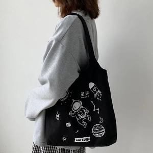 Detailed view of the black canvas tote bag featuring astronaut and space silk print
