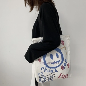 Close-up of white canvas tote bag featuring street art graffiti and bear graphics