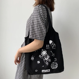 Detail view of black canvas tote bag with white astronaut and planet space theme prints