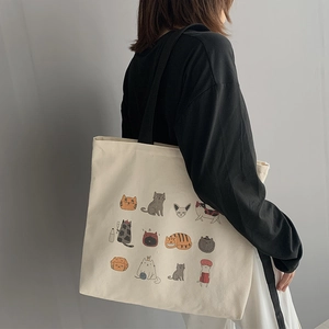 Détail du sac cabas en toile avec douze motifs de chats de dessin animé et bandoulière noire