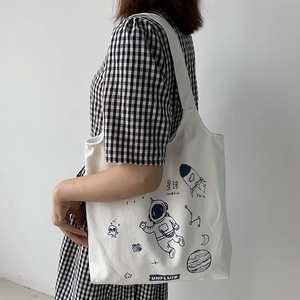 Close-up of white canvas tote bag with hand-drawn space theme astronaut illustrations