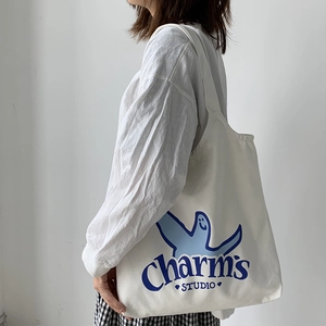 Detail of off-white canvas tote bag featuring blue artistic cartoon print and sturdy straps