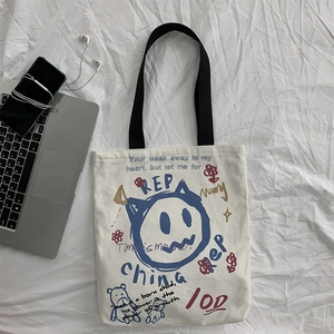 Flat lay of off-white canvas tote bag with street style cat graffiti and laptop