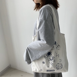 Detail of white canvas tote bag with astronaut print and spacious inner compartment