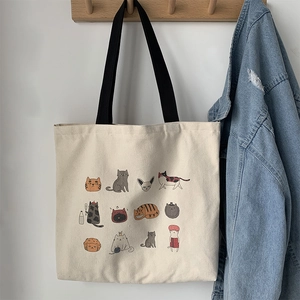 Détail d'un sac fourre-tout en toile beige avec illustrations de chats et anses