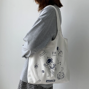 Detail of white canvas tote bag featuring hand-drawn space astronaut illustrations