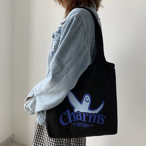 Detail of black canvas tote bag featuring light blue cartoon print and shoulder strap