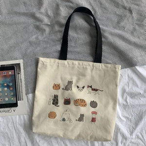 Détail du sac cabas en toile avec plusieurs chats mignons et des anses noires solides