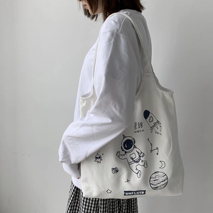 Detail of off-white canvas tote featuring space astronaut print worn on the shoulder