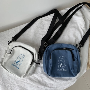Detail view of canvas crossbody bags with cartoon rabbit print and zipper pockets