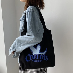 Detail of black canvas tote bag with blue ghost print and Charm's STUDIO text logo