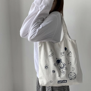Detail of white canvas tote bag with space-themed astronaut and rocket illustrations