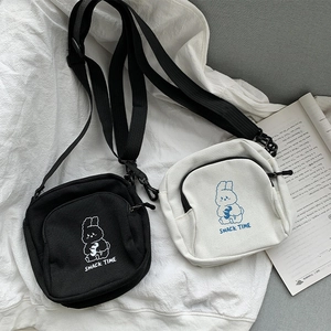 Close-up of black and cream canvas messenger bags with cute rabbit cartoon illustrations