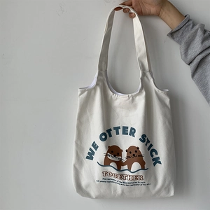 Detail der weißen Stofftasche mit Otter-Cartoon und Text WE OTTER STICK TOGETHER