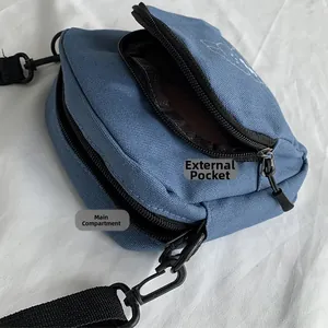 Detail view of the blue canvas crossbody bag showing dual zipper pockets and interior space