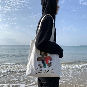 Photo en extérieur d'un sac cabas blanc en toile avec un ours graffiti et l'imprimé GAME