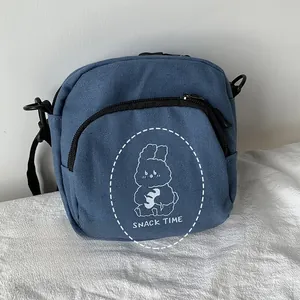 Detail of navy blue canvas bag featuring white cartoon rabbit print and snack time text