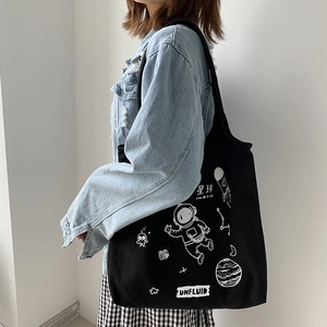 Detailed side view of black canvas tote bag featuring astronaut and space illustrations